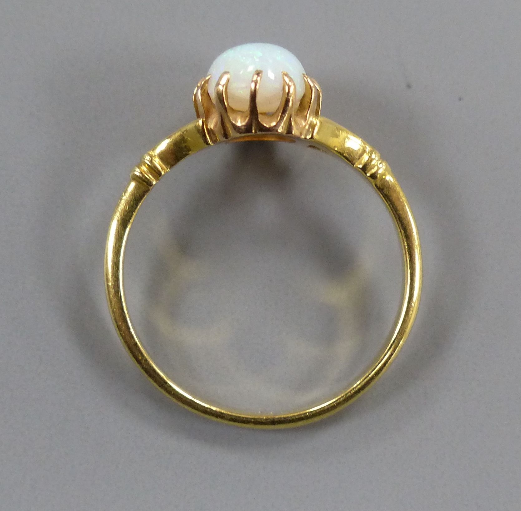 A yellow metal and cabochon oval white opal set dress ring, size O, gross 2.7 grams.